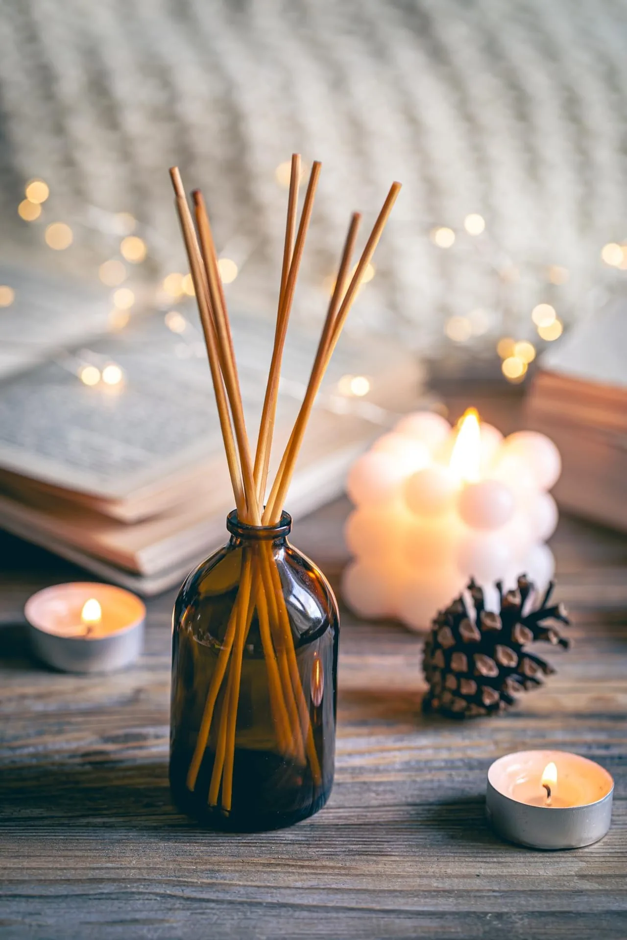 Reed diffuser in a glass vessel on a shelf beside dried botanicals