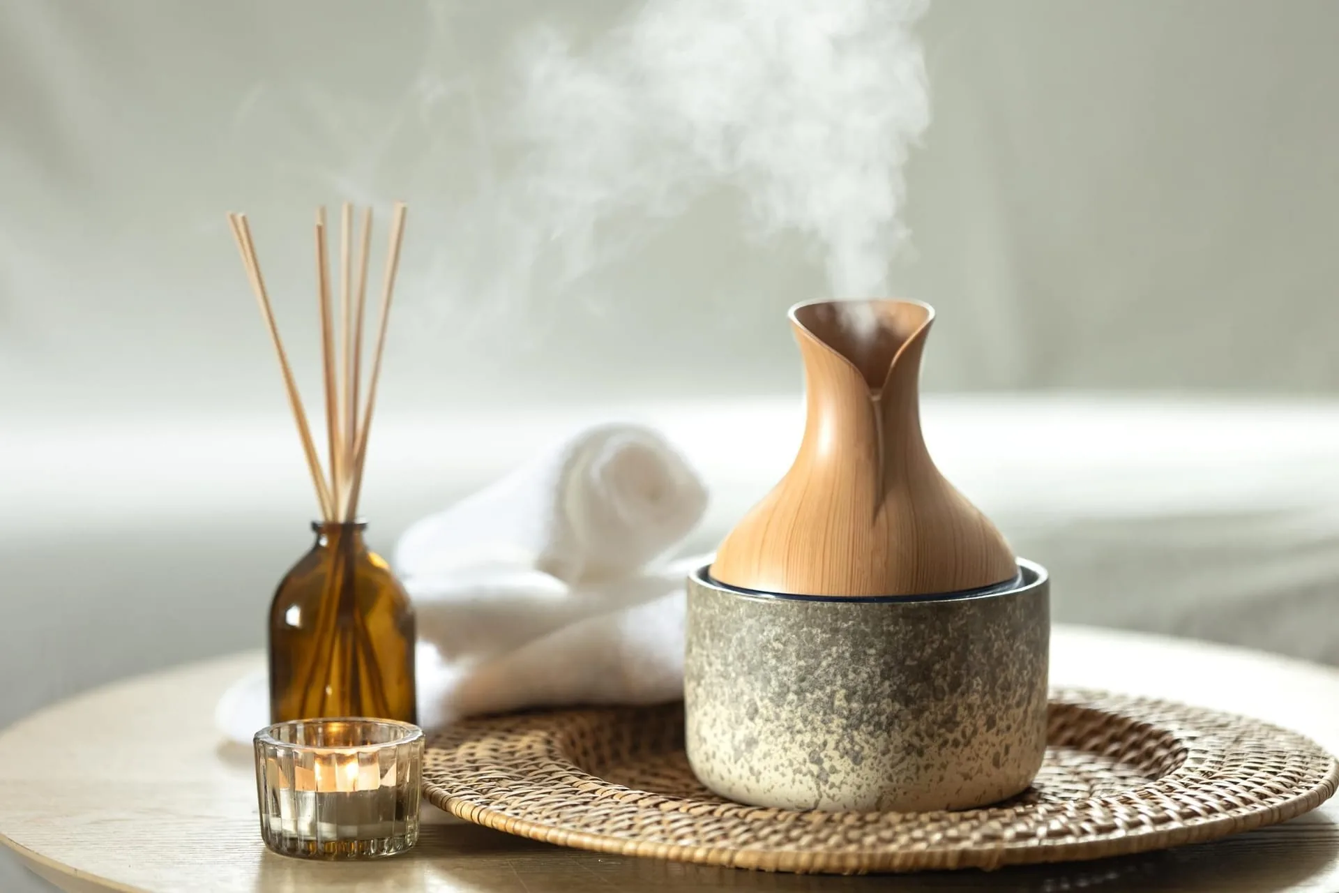A reed diffuser in amber glass resting on a quiet shelf at dusk